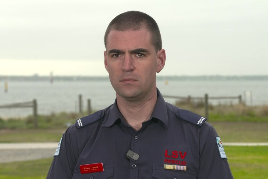 Kane Treloar wearing life saving victoria uniform standing in front of beach.
