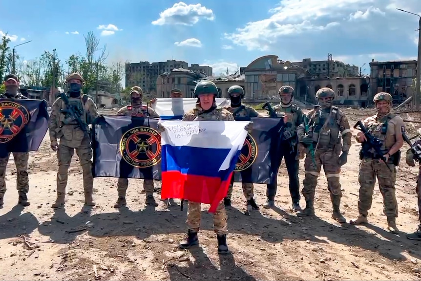 Yevgeny Prigozhin, head of the Wagner private military contractor, holds a Russian flag in front of his troops.