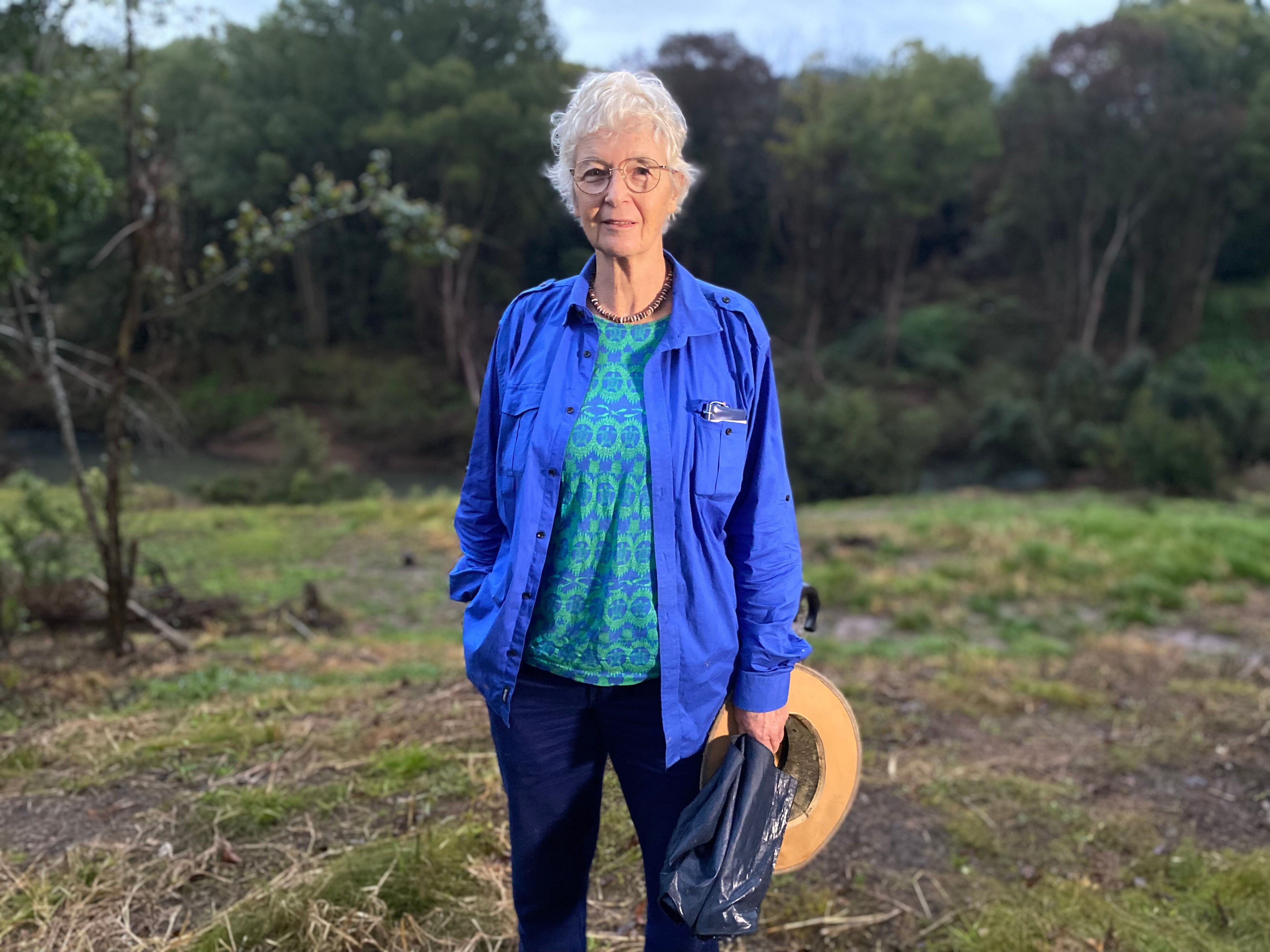 A woman stands outside wearing a blue jacket.
