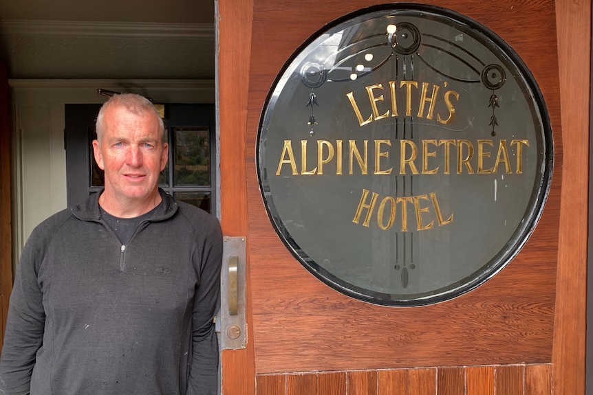 A photo of Anthony standing next to a sign for the Alpine Retreat hotel in Leith 