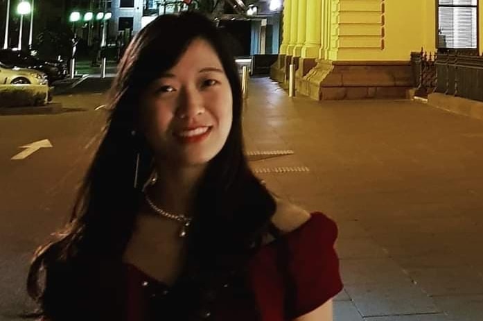 Meimi Wong smiling at night in front of a building,