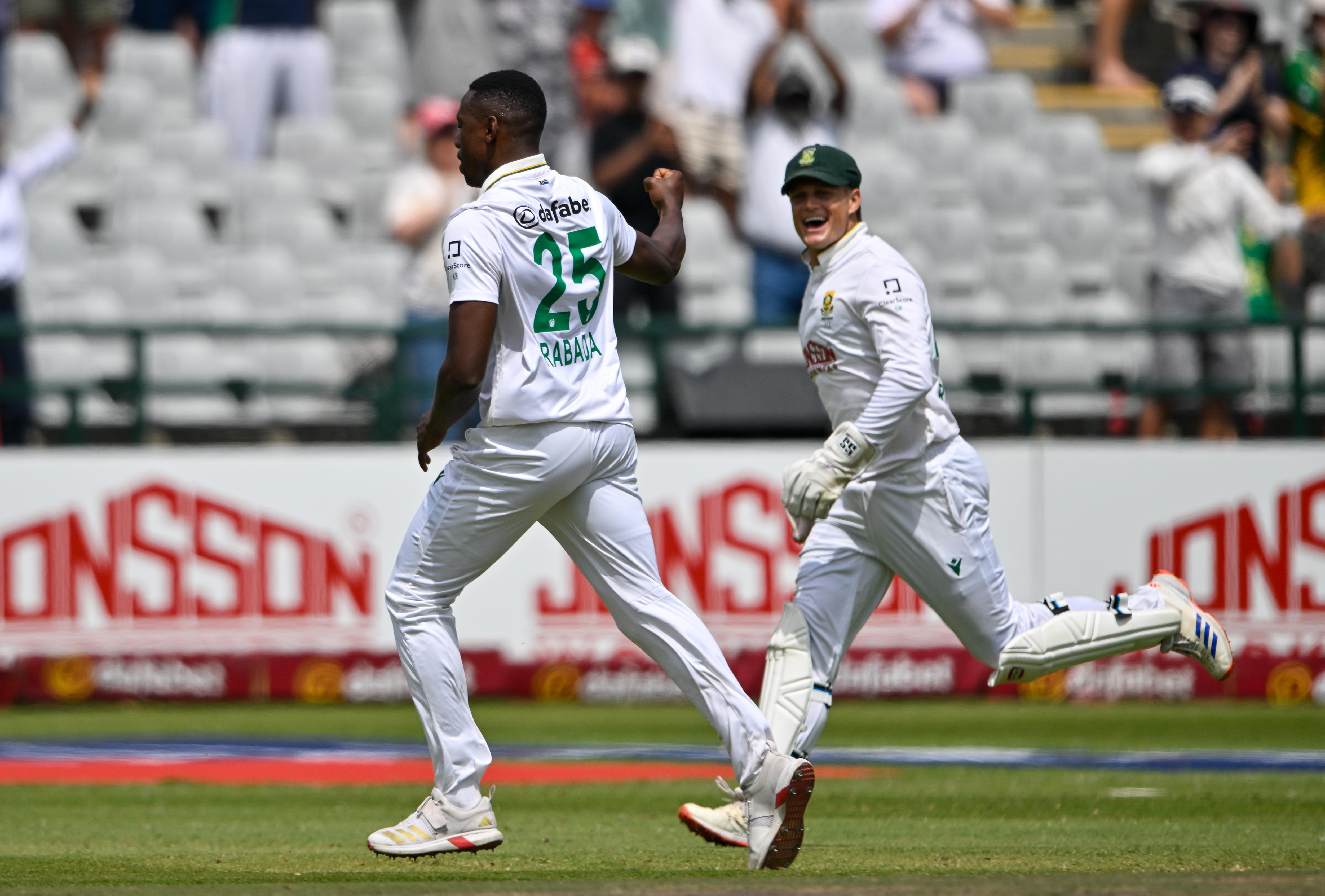 Two cricketers in white celebrate a wicket