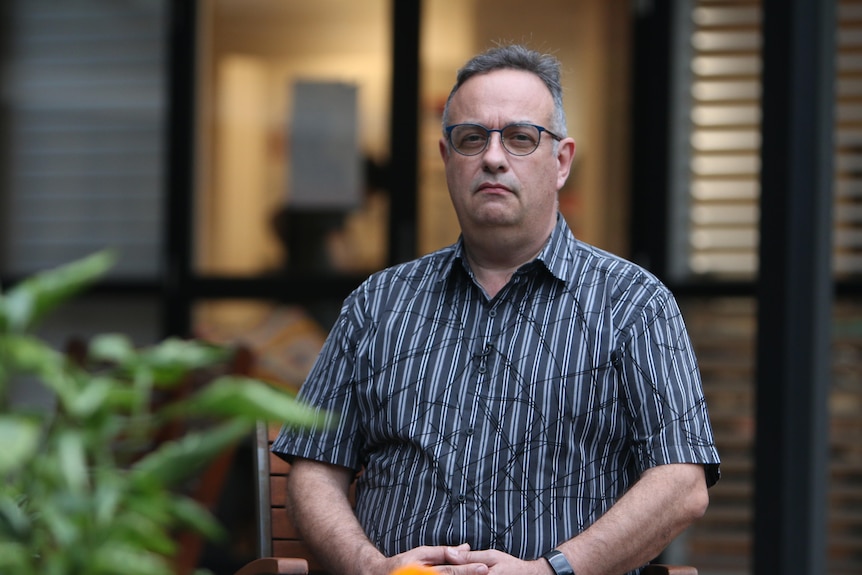 Paul Adderley looks serious and determined as he looks into the camera, wearing a collared shirt.