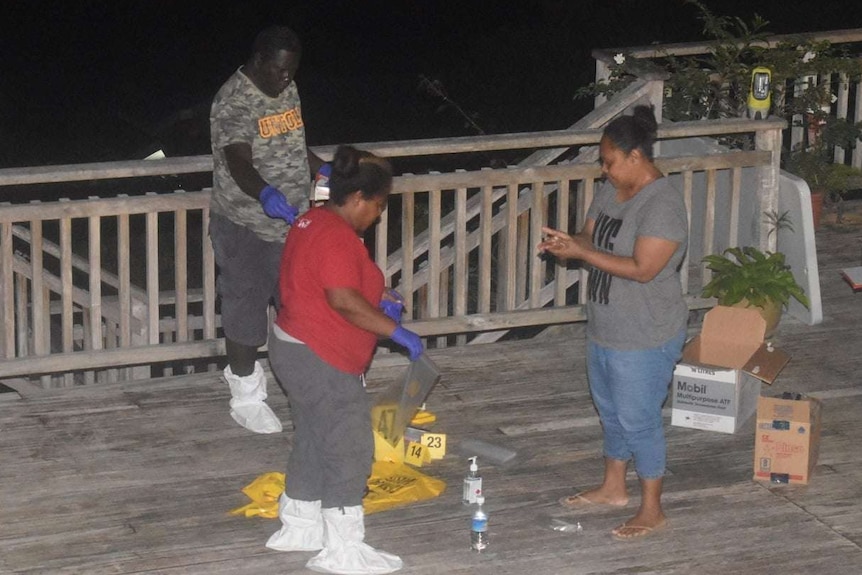 Four people in the shot, with gloves and protective equipment with crime scene numbers at their feet