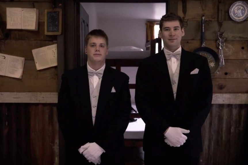 Two young men, wearing suits, getting ready for a debutante ball.