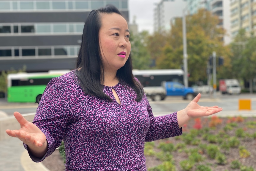 A woman with black hair in a purple shirt speaks passionately.