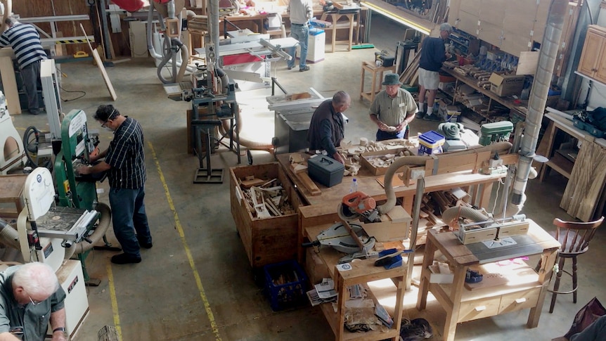 A bird's eye view of a large shed with men at different woodworking stations.