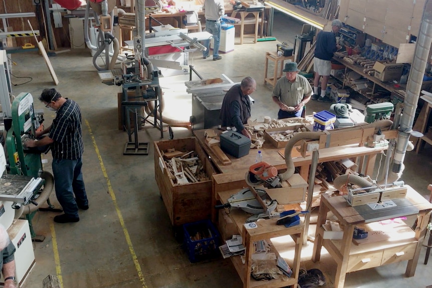 A bird's eye view of a large shed with men at different woodworking stations.