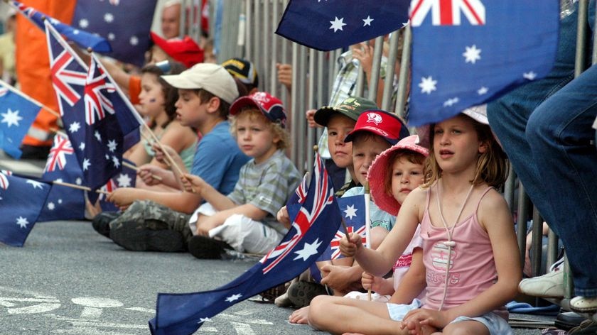 Children waving the Australian flag at Anzac parade in Brisbane.