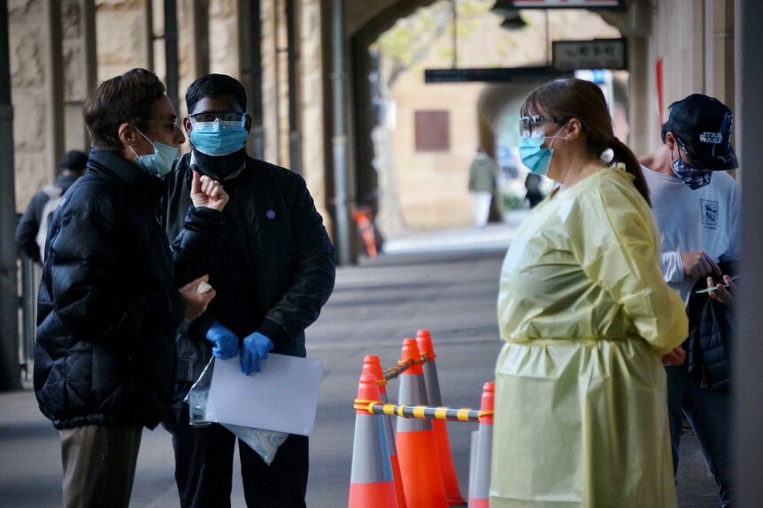 A masked man speaks with staff at a COVID-19 clinic in Sydney