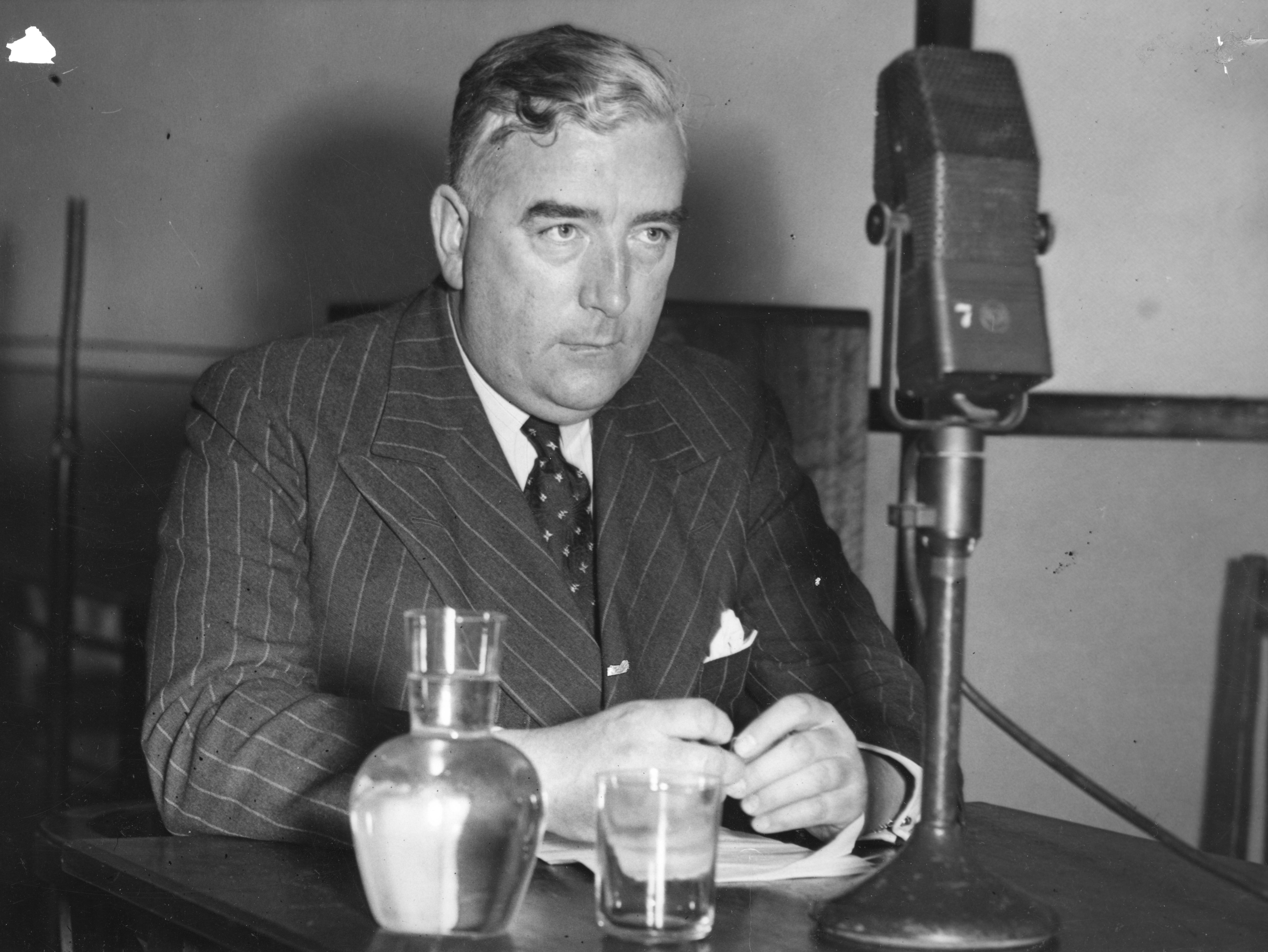Black and white photo of Menzies in front of a radio microphone.