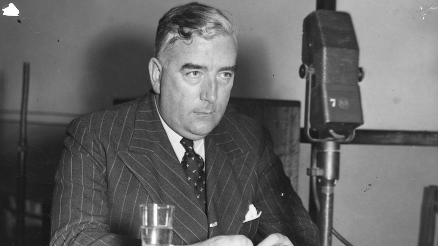 Black and white photo of Menzies in front of a radio microphone.