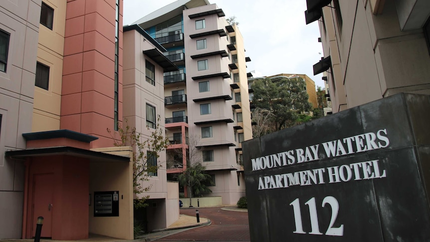 Entrance sign to Mounts Bay Waters Apartment Hotel with high rise buildings in the background.