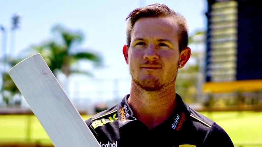 D'Arcy Short holding a cricket bat and wearing a black T-shirt with logos on it at the WACA ground.