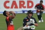 Mohammad Saifuddin kisses his hands and looks up next to Tom Latham tucking his bat under his arm 