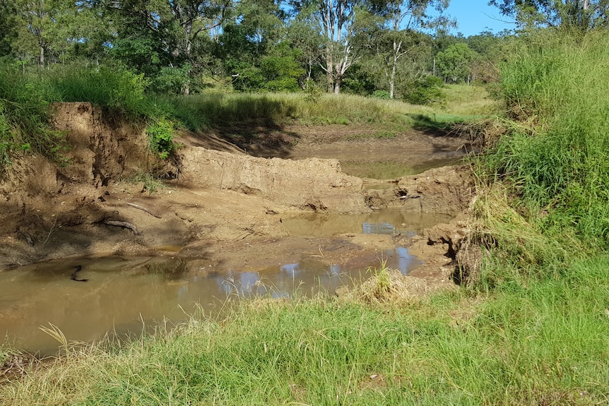 Looking upstream towards a dam that is a mess of mud.