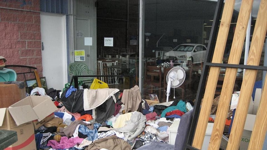 A pile of clothes and household goods outside a charity shop.
