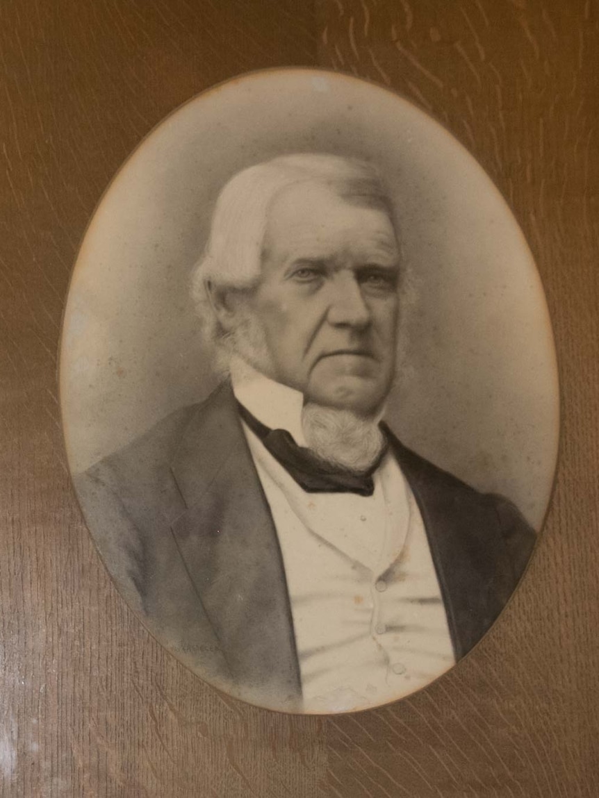 Black and white photograph in a frame of a man dressed in suit from the 1800s