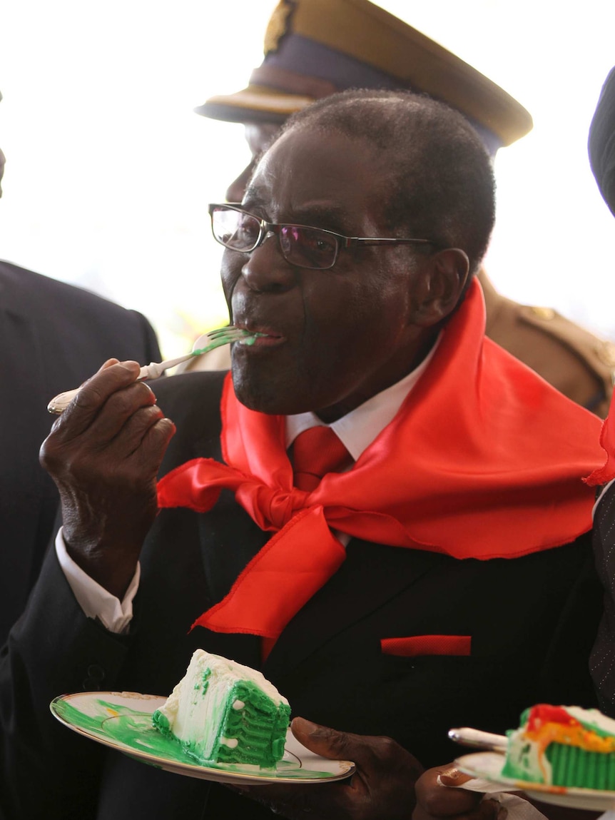 Zimbabwe's president Robert Mugabe eats a slice of cake during celebrations marking his 90th birthday.