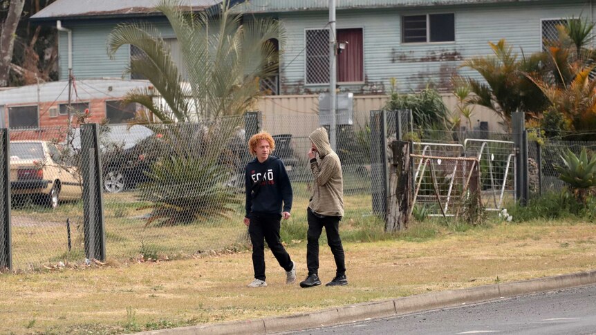 Two teenage boys walk past front yards