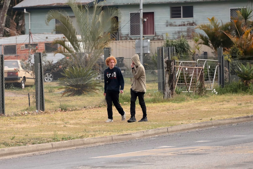 Two teenage boys walk past front yards