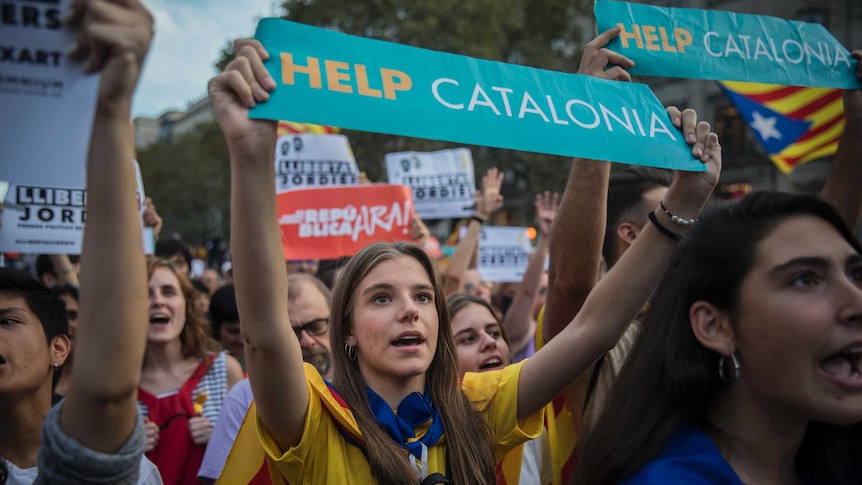 Catalan protesters hold up a sign that reads Help Catalonia.