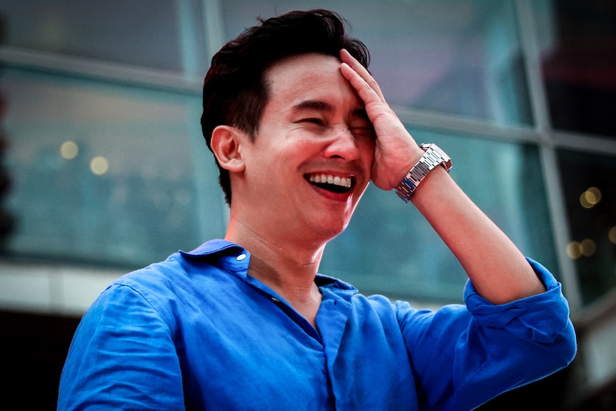 A young Thai man laughing and touching his head