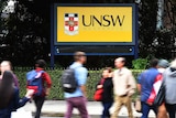 Students walk past a yellow sign that says UNSW
