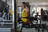 A man sitting on a gym machine doing weights.