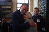 Arnold Schwarzenegger, left, hugs Holocaust survivor Lydia Maksimovicz, right.