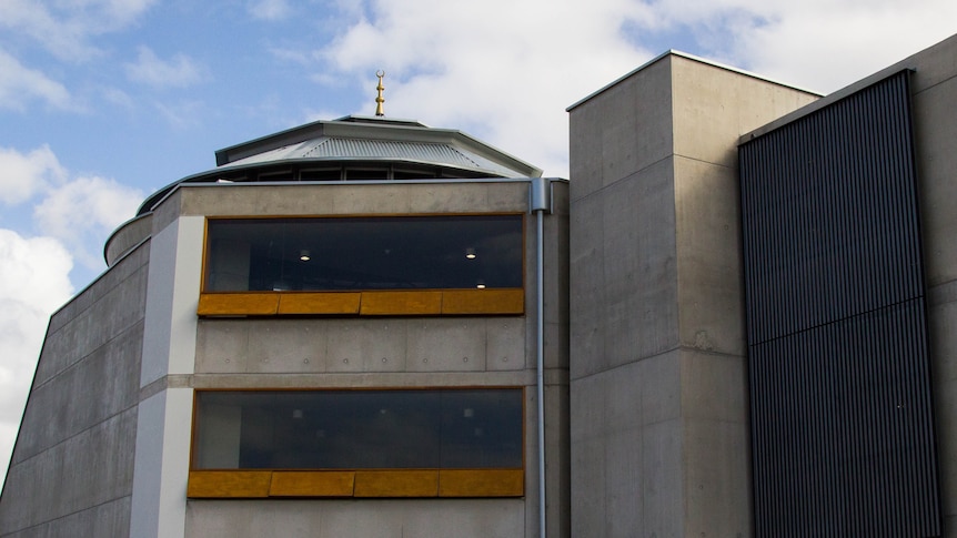 Outside of Punchbowl mosque, a cement building with wood accents and a domed tin roof.