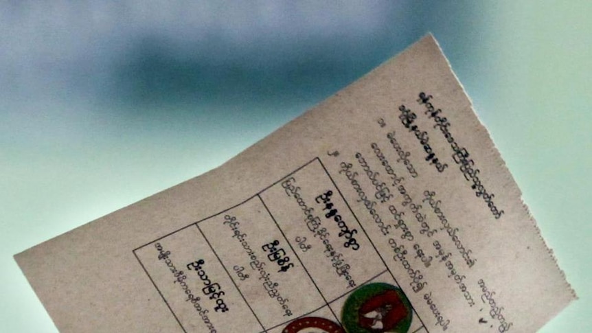 An election official holds up a ballot paper at a vote counting centre in Yangon, Burma