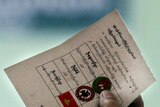An election official holds up a ballot paper at a vote counting centre in Yangon, Burma