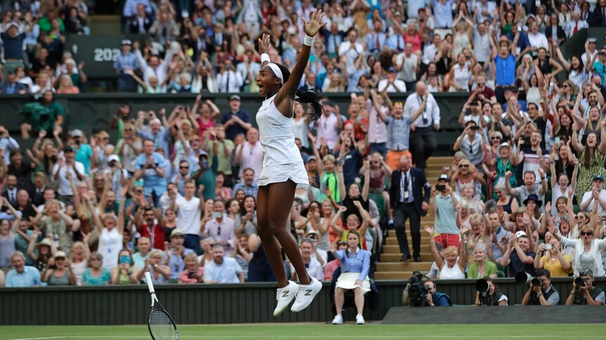 Coco Gauff jumps in the air with her hands held high.
