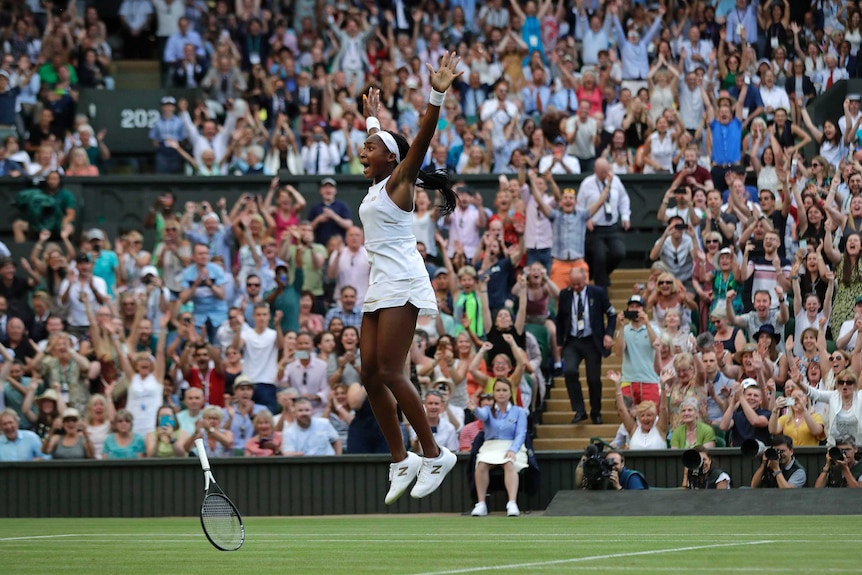 Coco Gauff jumps in the air with her hands held high.