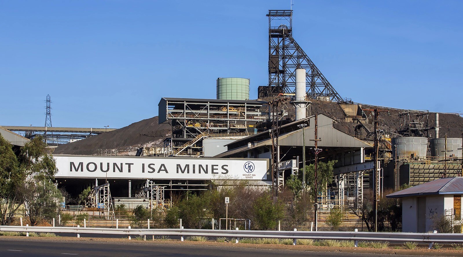 A mid shot of the exterior of an underground copper mine with a sign that reads "Mount Isa Mines" in bold text