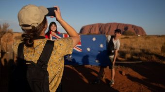 A woman takes a photo near Uluru.