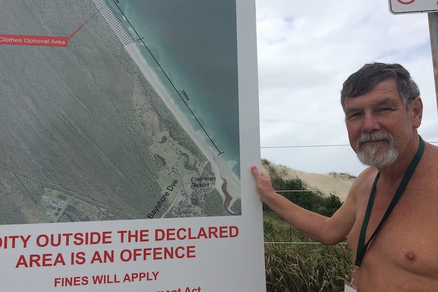President of the Australian Naturalist Federation, Greg Serow, stand beside a sign indicating the area for clothes-optional bath
