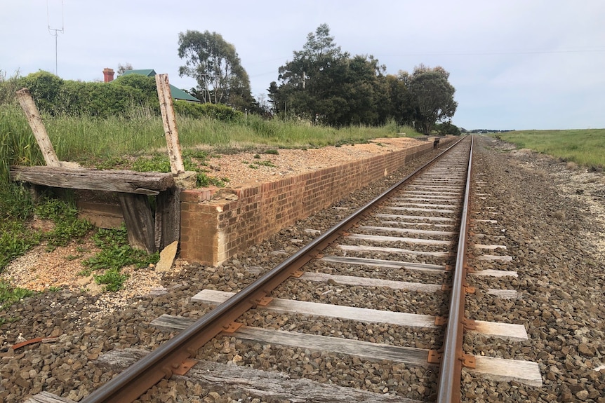 Crumbling railway platform alongside still functional railway line