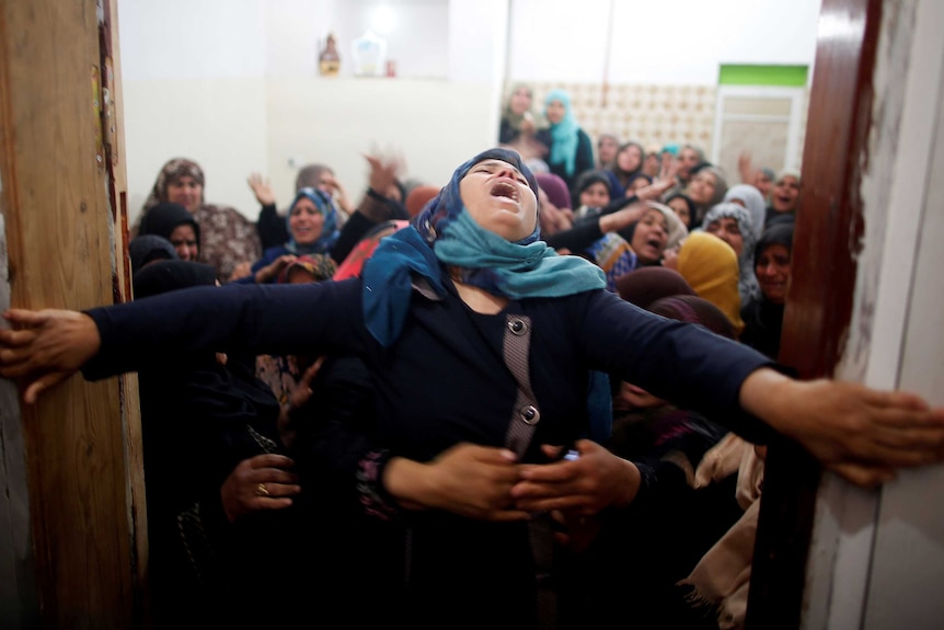 Mourners hold back a relative of Palestinian Hamdan Abu Amshah during his funeral.