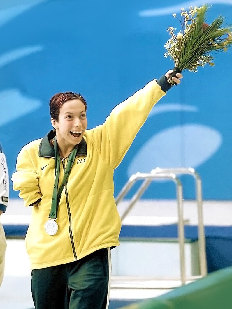 A young female Paralympian holding flower while celebrating winning a silver medal