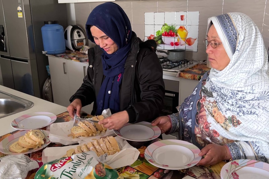two Afghan women prepare a meal in a kitchen