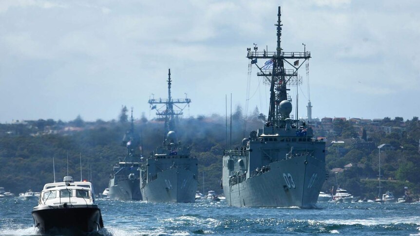 A line of warships make their way through Sydney Harbour for the International Fleet Review.