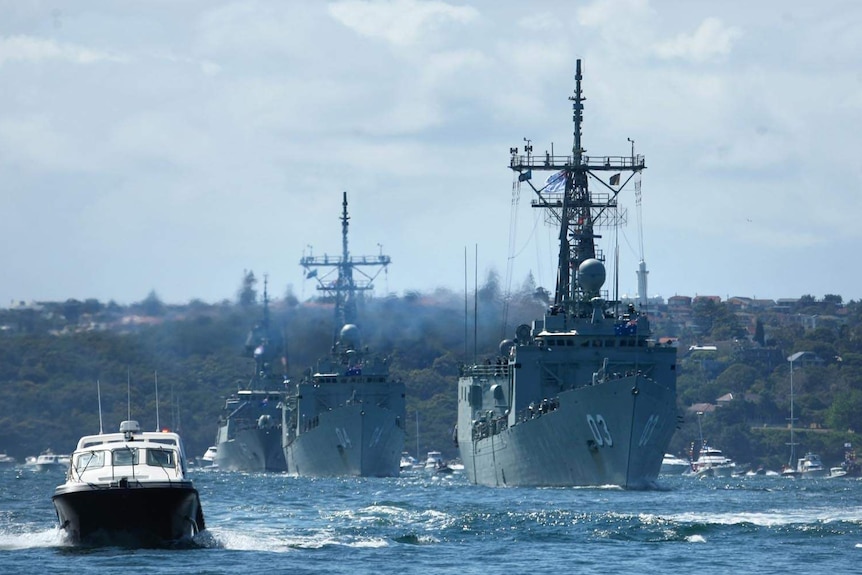 A line of warships make their way through Sydney Harbour for the International Fleet Review.
