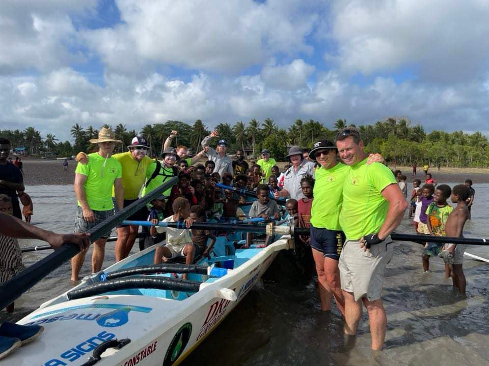 A group of rowers mix with Papua New Guinea residents on a surf boat.