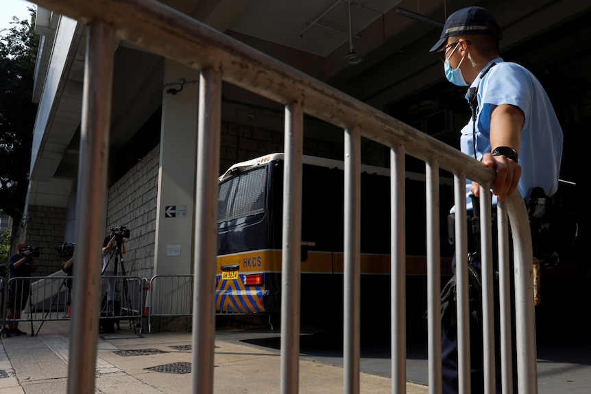 Police stand guard as a prison vehicle arrives at a court during the hearing