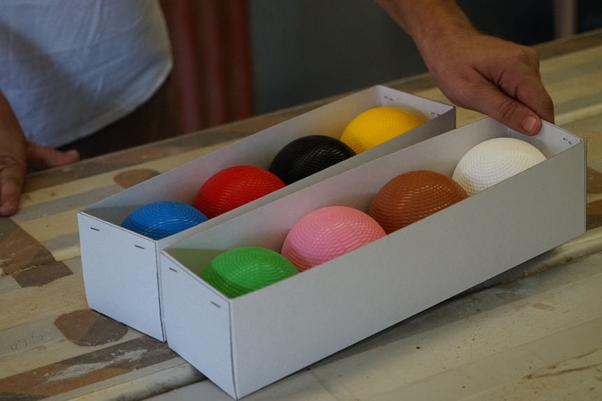 The different coloured croquet balls in a white box with no lid