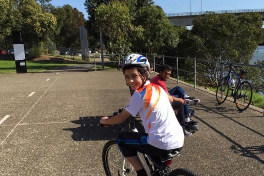 Teenage boy rides a bike smiling. 