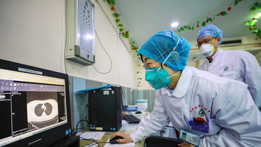 Doctors look at a CT scan of a patient at a hospital in Wuhan in central China's Hubei Province, Thursday, Jan. 30, 2020.