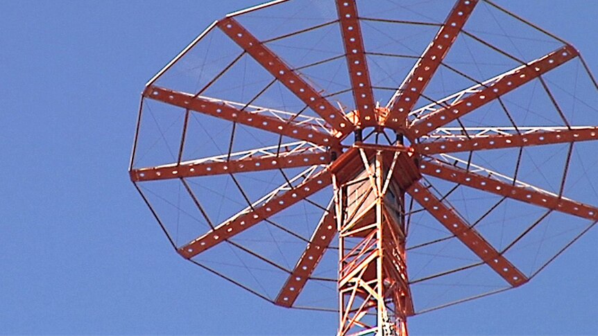The top of a radio transmitter tower against clear blue sky.